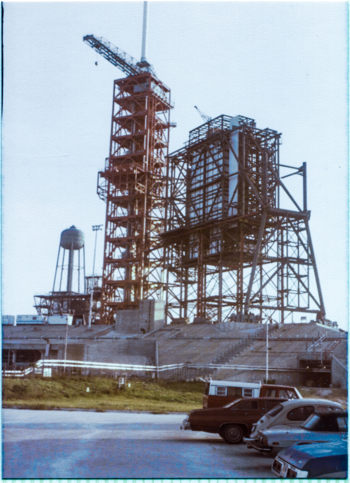 Image 005. The Great Rotating Service Structure at Space Shuttle Launch Complex 39-B, Kennedy Space Center, Florida, begins to take on its final outlines as it continues to be assembled by the Union Ironworkers of Local 808 working for Wilhoit Steel Erectors, using structural steel that was fabricated by Sheffield Steel. You are viewing it from just in front of Sheffield’s trailer in the parking lot which fronted the row of field trailers where the contractors who did the work managed their portions of the overall project, looking northeast on a crisp autumn Florida morning. Photo by James MacLaren.